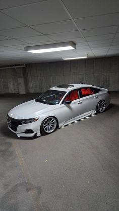 a white car is parked in an empty parking garage with its door open and lights on