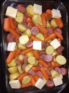 there are many different types of food in the trays on the table, including carrots, potatoes and sausage