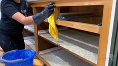 a person cleaning shelves with a yellow cloth