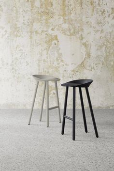 two stools sitting next to each other in front of a wall