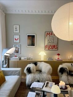 a living room filled with white furniture and lots of pictures on the wall above it