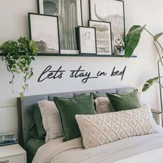 there is a bed with pillows and pictures on the wall above it that says let's stay in bed