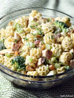 a glass bowl filled with pasta salad on top of a green and white table cloth