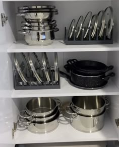 pots and pans are sitting on shelves in a kitchen cupboard with utensils