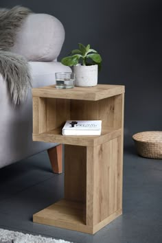 a corner table with a book on it in front of a white chair and grey wall