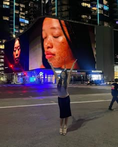 a woman is holding up a large billboard in the middle of an empty city street