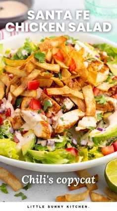 a salad with chicken, lettuce and tomatoes in it next to some chips