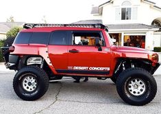 a red hummer truck parked in front of a house with the words desert concepts on it