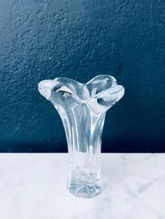 a clear glass vase sitting on top of a white marble table next to a blue wall