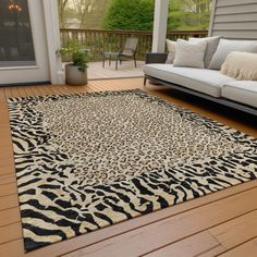 a living room area with couches and rugs on the wooden flooring outside