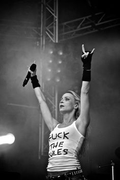 a woman with her hands up in the air while performing on stage at a concert