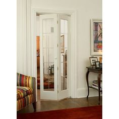 a living room filled with furniture and a white door leading to a hallway that has glass panels on the doors