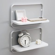 two white shelves with one clock and the other on it's sides, each holding a small pig figurine