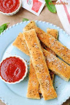 some bread sticks on a plate with ketchup and sauces next to it