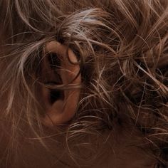 a close up of a person's ear with hair blowing in the wind