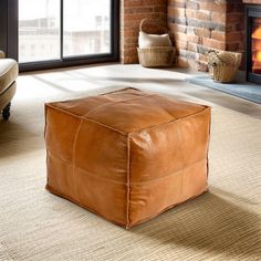 a living room with a fire place and leather ottoman