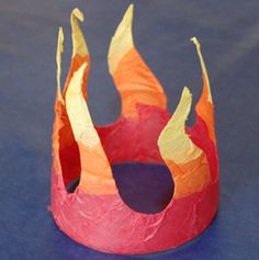 a paper crown sitting on top of a blue table next to an orange and pink piece of paper