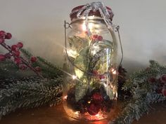 a glass jar filled with christmas greenery and lights