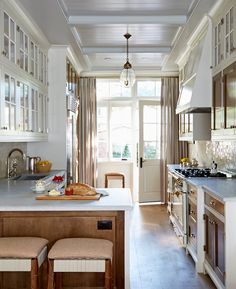 a kitchen with wooden floors and white cabinets, along with two stools on the counter