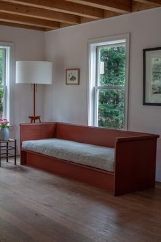 a living room filled with furniture next to two windows and a lamp on top of a wooden floor