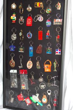 a shadow box with many different keychains and medals in it on a white sheet