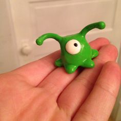 a small green toy with googly eyes in someone's hand