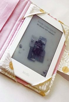 an electronic device is sitting on top of a pink and white cloth covered book case