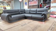 a black leather couch sitting on top of a wooden floor next to a green truck