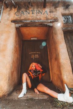 a woman sitting on the ground in front of a building