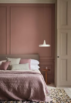 a bedroom with pink walls and bedding in the corner, along with an area rug on the floor