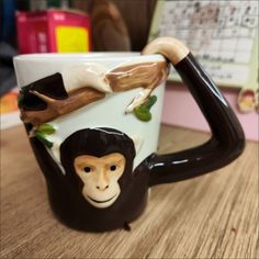 a ceramic monkey mug sitting on top of a wooden table