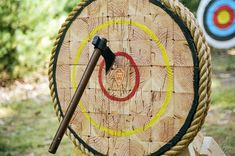 a wooden target with an arrow stuck in it next to a roped bow and arrows