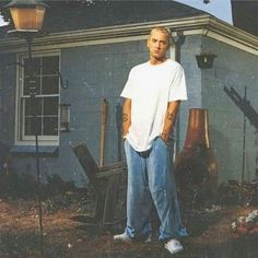 a man standing in front of a house with his hands on his hips and looking at the camera