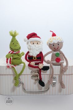 three crocheted elves sitting on top of a white piece of luggage with handles