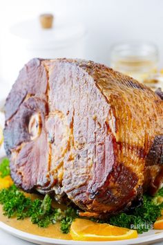 a ham is sitting on a plate with orange slices and parsley around the edges