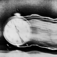 a black and white photo of an alarm clock with motion blurry in the background