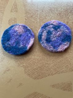 two purple and blue buttons sitting on top of a table