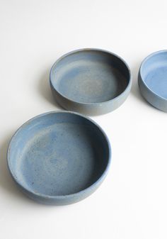 three blue bowls sitting on top of a white table