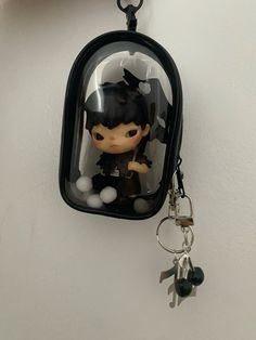 a key chain hanging from the side of a wall with a small doll in it