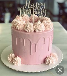 a pink birthday cake with white frosting and flowers on the top that says happy birthday