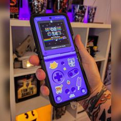 a person holding up a cell phone with gameboy stickers on the display case