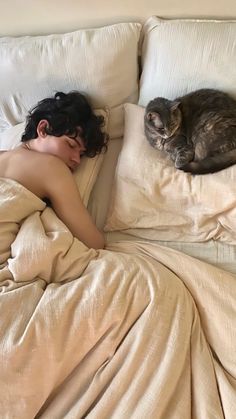 a woman laying in bed next to a cat