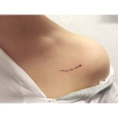 a small tattoo on the back of a woman's left shoulder, with an arrow