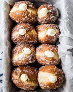 a box filled with lots of powdered sugar covered doughnuts