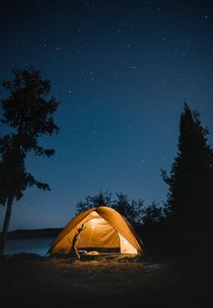 a tent is lit up at night with the stars shining in the sky above it