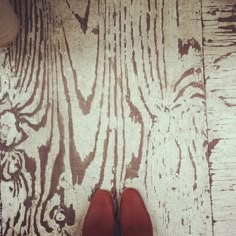 a pair of red shoes sitting on top of a wooden floor next to a wall