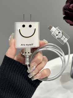 a woman is holding an electric device with a smiley face on it and plugged in