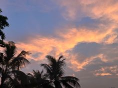 the sky is filled with clouds and palm trees