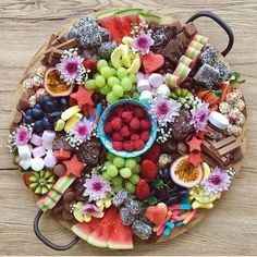 a platter filled with fruit and chocolates on top of a wooden table,