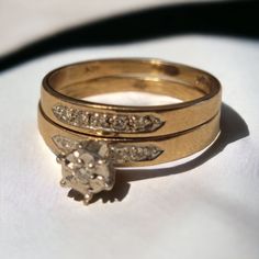 two gold wedding rings with diamond accents on each one and an engagement ring in the other